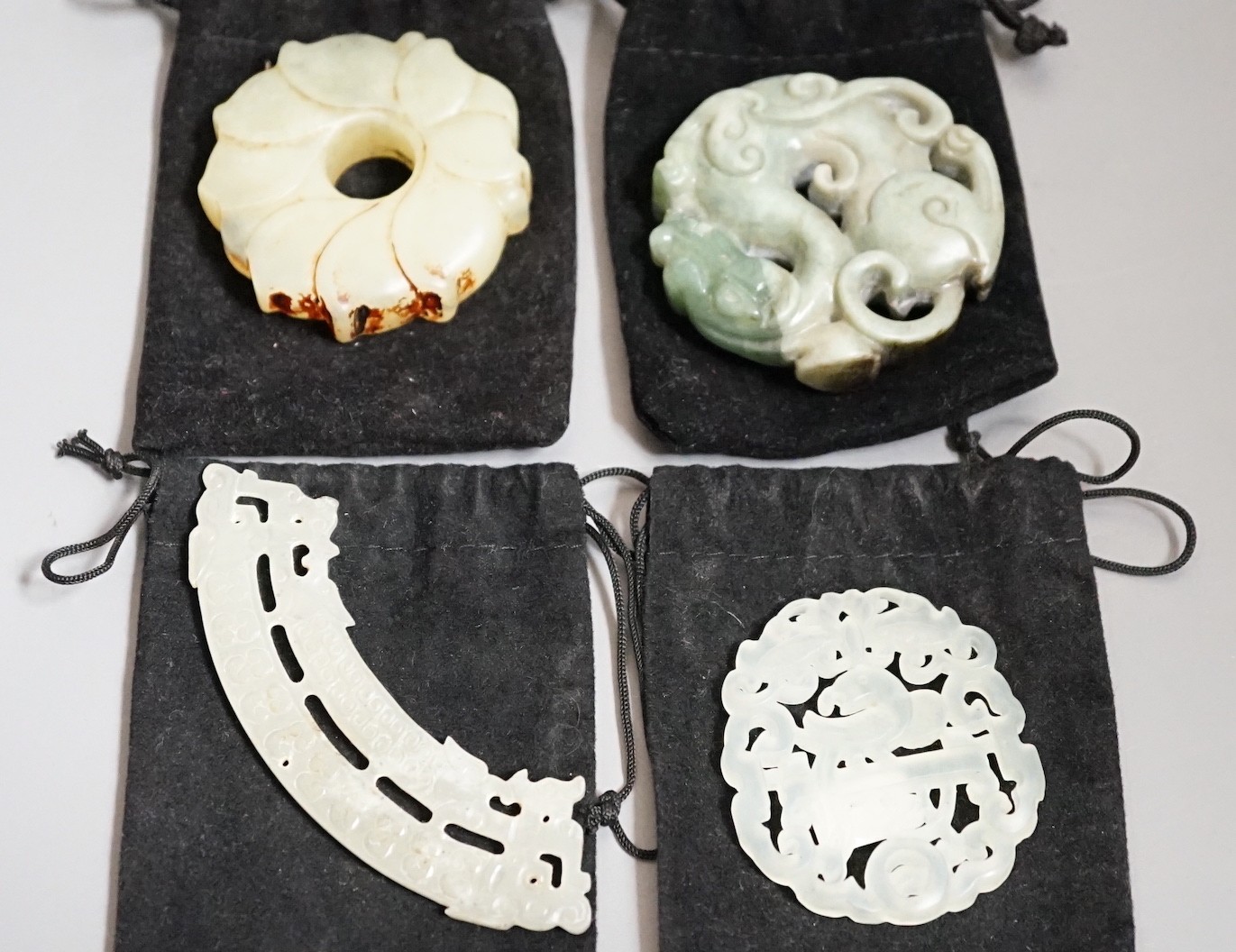 Three Chinese jade celadon roundels/pendants and a huang plaque, carved dragon roundel 5.5 cms diameter (4)